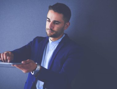 Gri arka planda yalnız oturan genç iş adamı