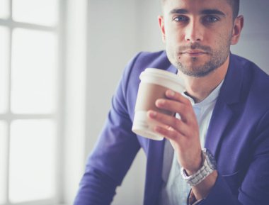 Gri arka planda yalnız oturan genç iş adamı.