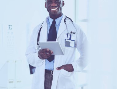 Tablet bilgisayarlı siyahi bir doktor hastanede bekliyor.