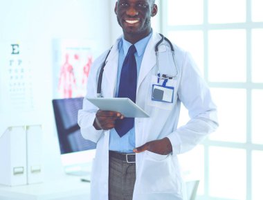 Tablet bilgisayarlı siyahi bir doktor hastanede bekliyor.