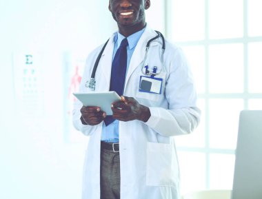 Tablet bilgisayarlı siyahi bir doktor hastanede bekliyor.