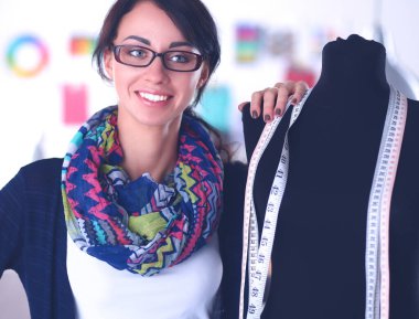 Gülümseyen moda tasarımcısı ofiste mankenin yanında duruyor.