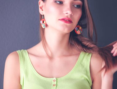 Gri duvarda gülümseyen genç bir kadının portresi.