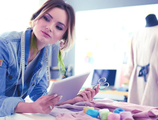 Diseñadora de moda mujer que trabaja con ipad en sus diseños en el estudio —  Fotos de Stock