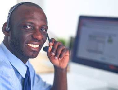 Kulaklıklı Afro-Amerikan işadamı laptopuyla çalışıyor.