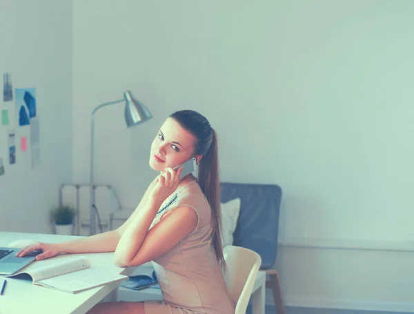 Joven mujer de negocios sentada en el escritorio y hablando por teléfono —  Fotos de Stock