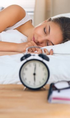 Güzel genç bir kadın, rahat ve mutlu bir şekilde yatakta uzanıyor.