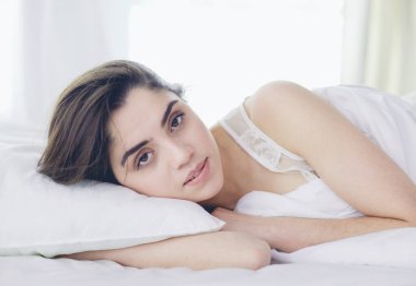Güzel bir kadın yatağında uzanıyor.