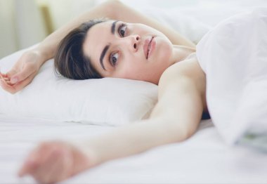 Güzel bir kadın yatağında uzanıyor.