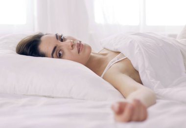 Güzel bir kadın yatağında uzanıyor.