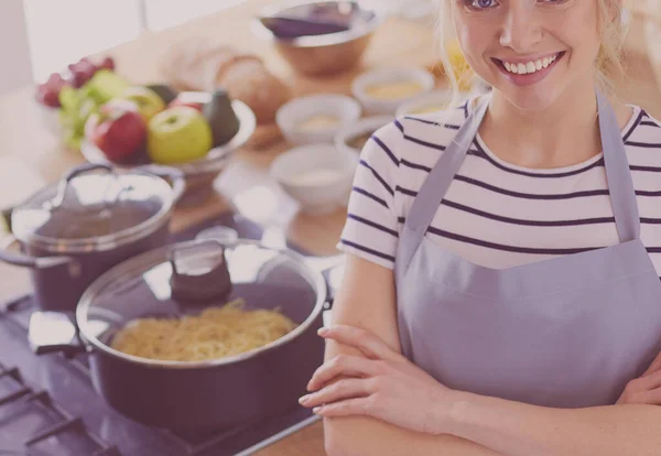 Mujer joven de pie cerca de escritorio en la cocina — Foto de Stock