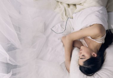 Güzel bir kadın yatağında uzanıyor.