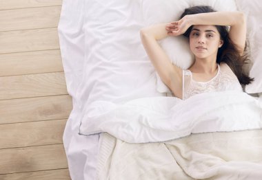 Güzel bir kadın yatağında uzanıyor.