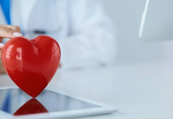 Médecin femme avec stéthoscope tenant le cœur, sur fond clair — Photo