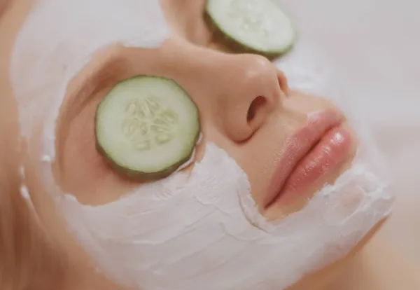 Mulher bonita recebendo máscara facial de pepino no salão de beleza — Fotografia de Stock