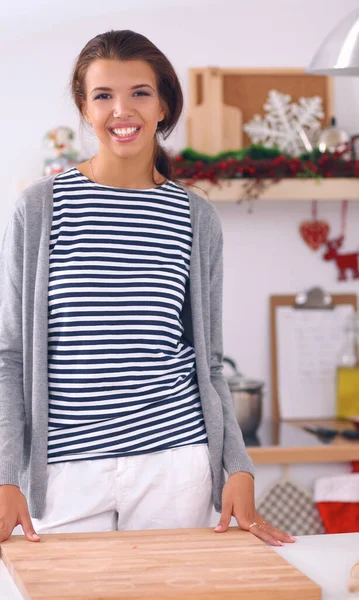 Glimlachende jonge vrouw in de keuken, geïsoleerd op kerst achtergrond — Stockfoto