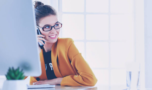 Бизнесмен, сидящая в офисе с ноутбуком по телефону
