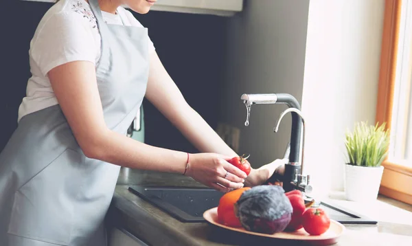 Vrouw wassen tomaten in keuken gootsteen close up — Stockfoto