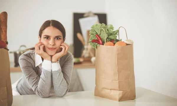 Young woman holding grocery shopping bag with vegetables . Standing in the kitchen — Stock Photo, Image