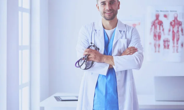 Jonge en zelfverzekerde mannelijke arts portret staan in medische off — Stockfoto