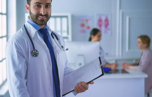 Χαμογελαστός γιατρός στέκεται μπροστά στην ομάδα του και ασθενής — Φωτογραφία Αρχείου