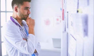 Genç ve kendinden emin erkek doktor portresi tıp ofisinde duruyor.