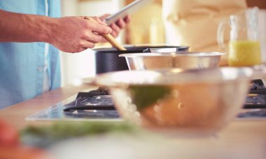 Dijital tablet ve yemek pişirme tarifine uyan bir adam evdeki mutfakta lezzetli ve sağlıklı yemekler pişiriyor.