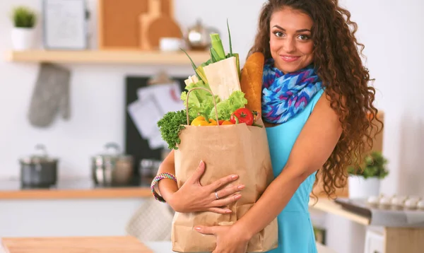Young woman holding grocery shopping bag with vegetables Standing in the kitchen. — Stock Photo, Image