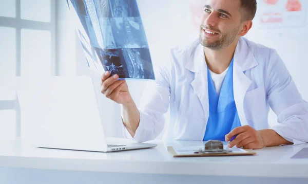 Genç doktor ofisinde oturuyor ve röntgen sonuçlarını inceliyor. — Stok fotoğraf