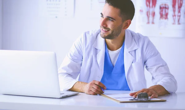 Portrait d'un médecin avec un ordinateur portable assis au bureau médical — Photo