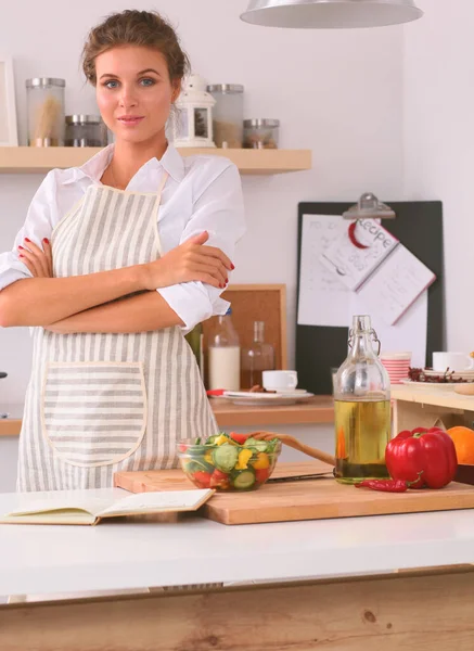 Glimlachende jonge vrouw in de keuken, geïsoleerd op kerst achtergrond — Stockfoto