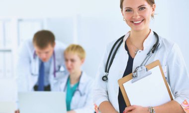 Tıbbî grubun önünde dosyası olan çekici bir kadın doktor.