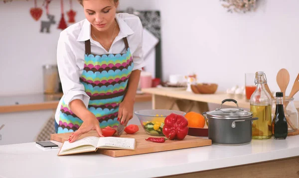 Jeune femme lecture livre de cuisine dans la cuisine, à la recherche de la recette — Photo