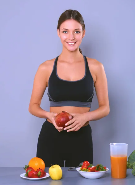 Mulher jovem e bonita de pé perto da mesa com legumes — Fotografia de Stock