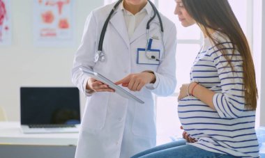 Hastanede doktorla gülümseyen güzel bir hamile kadın.