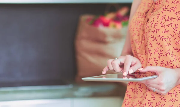 Piękna młoda kobieta za pomocą tabletu cyfrowego w kuchni. — Zdjęcie stockowe