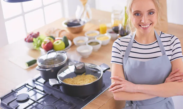 Jovem mulher de pé perto da mesa na cozinha — Fotografia de Stock