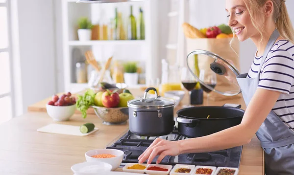 Evdeki mutfakta yemek pişiren güzel genç bir kadın.