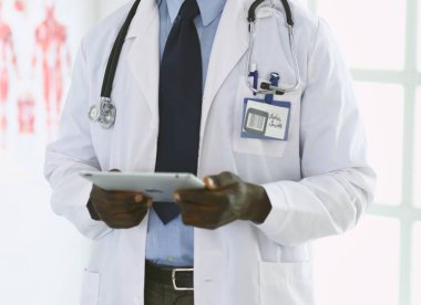 Tablet bilgisayarlı siyahi bir doktor hastanede bekliyor.