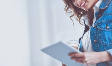 Gülümseyen kadın kahve içiyor ve kafede tablet kullanıyor.