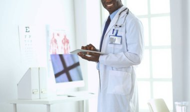 Tablet bilgisayarlı siyahi bir doktor hastanede bekliyor.
