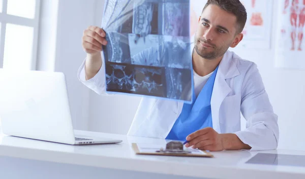 El guapo doctor está hablando con una paciente joven y tomando notas mientras está sentado en su consultorio.. — Foto de Stock