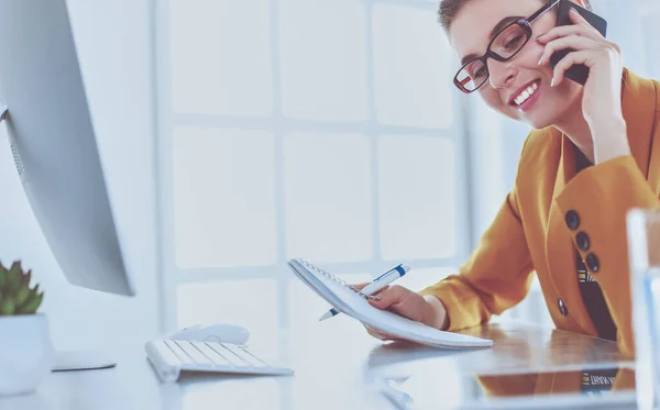 Retrato de una hermosa mujer haciendo una llamada mientras está sentada en su lugar de trabajo frente a la computadora portátil y trabajando en un nuevo proyecto — Foto de Stock