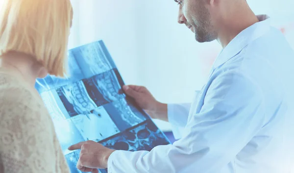 Médico bonito está conversando com jovem paciente do sexo feminino e fazendo anotações enquanto está sentado em seu escritório. — Fotografia de Stock