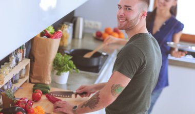 Bir çift evdeki mutfaklarında birlikte yemek pişiriyor.