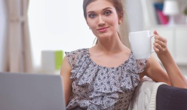 Elinde belgelerle masanın üstünde oturan gülümseyen kadın..