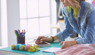 Moda tasarımcısı kadın stüdyoda tasarımları üzerinde çalışıyor.