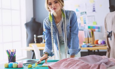 Moda tasarımcısı kadın stüdyoda tasarımları üzerinde çalışıyor.