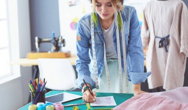 Moda tasarımcısı kadın stüdyoda tasarımları üzerinde çalışıyor.