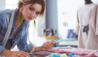 Moda tasarımcısı kadın stüdyoda tasarımları üzerinde çalışıyor.